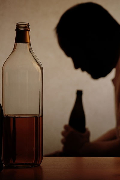 мужчина среди бутылок алкоголя